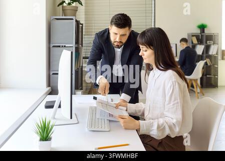 Manager coacht Mitarbeiter bei der Datenanalyse am Desktop in moderner Büroumgebung Stockfoto