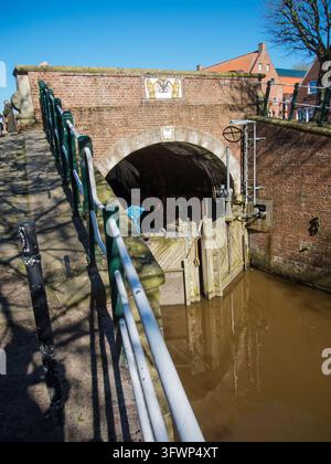 Ein erhöhter Blick auf das hölzerne Schleusentor in Greetsiel, Ostfriesland, gesehen vom Geländer am Schleusenbecken bei sonnigem Wetter vor einem blauen Himmel. Stockfoto