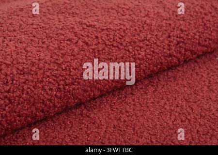 Rote Karakul-Abstrakt-Kunstpelztextur, Stoff, Hintergrund, Nahaufnahme. Flauschiger Materialhintergrund, Kinderspielzeug-Kunstfell Stockfoto