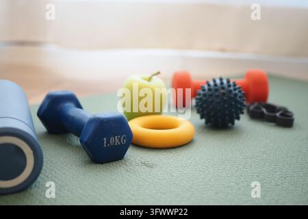 Fitnessgeräte und ein Apfel, arrangiert für eine Trainingseinheit Stockfoto