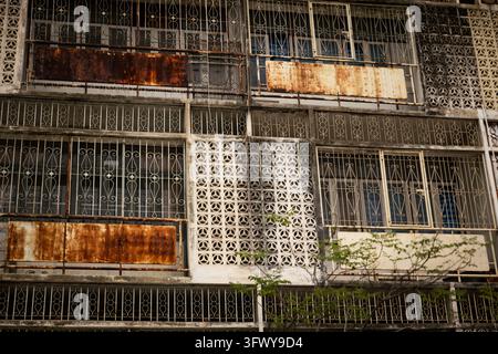 Bangkok, Thailand - 31. Januar 2026: Nahaufnahme der Fassade eines alten Gebäudes mit verrosteten Sicherheitsgittern und dekorativen Betonblöcken. Stockfoto