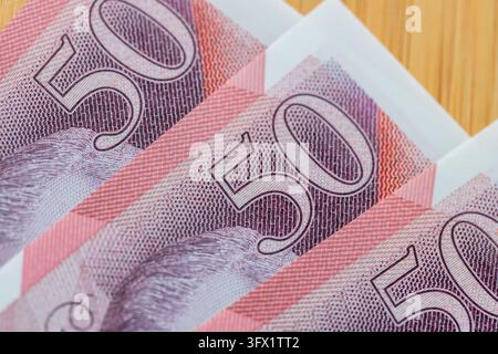 Britische Währung und Finanzkonzept mit gestapelten Fünfzig-Pfund-Noten, Makroaufnahme und nahtlosem Mustergrund. Stockfoto