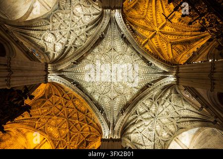 Aufblick zu kunstvollen gotischen Kreuzrippengewölben und geschnitzter Steindekoration im Inneren der Kathedrale von Sevilla, Andalusien, Spanien. Stockfoto