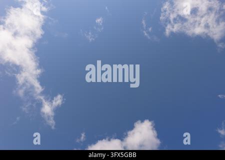 Blauer Himmel umrahmt weiße flauschige Kumuluswolken an einem sonnigen Tag Stockfoto
