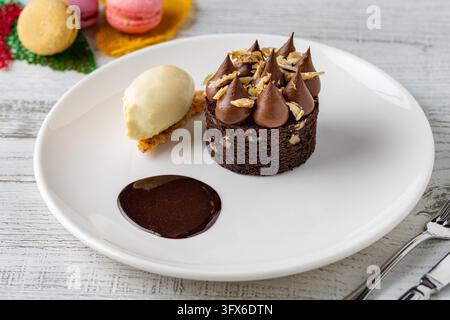 Schokoladen-Brownie-Kuchen mit Ganache-Höhen, Nüssen, Vanilleeis und Schokoladensoße Stockfoto