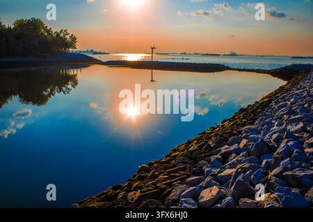 Ein See in einem Park in der Nähe des Flusses, Sonnenuntergang über dem Wasser, eine Felswand Stockfoto