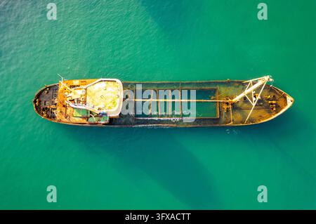 Verlassenes verrostetes Frachtschiff in türkisfarbenem Wasser Stockfoto