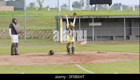 Verschiedene Senior-Schiedsrichter und Fänger feiern Spiel mit Drahtgesichtsschutz auf schmutzigem Infield, Kopierraum. Schiedsrichter, Athlet, Feier, Sport, Teamarbeit, Outd Stockfoto