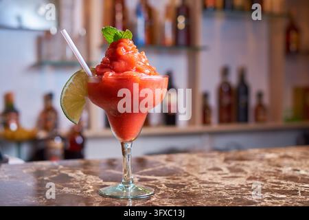 Gefrorener Erdbeer-Daiquiri-Cocktail, garniert mit Limette und Minze in einem Stielglas. Stockfoto