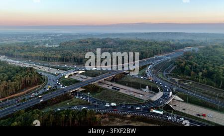 Luftbilddrohnenansicht der M25 Anschlussstelle 10 und der A3 Wisley Kreuzung mitten im Wald von Surrey, England Stockfoto