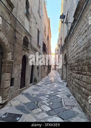 Schmale steingepflasterte Gasse zwischen alten Kalksteinhäusern im historischen Zentrum von Trani, Apulien, Italien, September 2026 Stockfoto