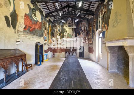 Spätgotische Fresken schmücken die Wände einer Halle mit Balkendecke und langem Holztisch im Palazzo Trinci, Foligno, Umbrien, Italien. Stockfoto