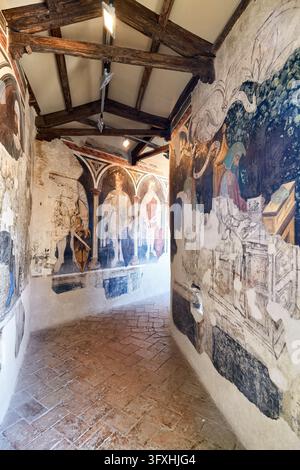 Verblasste Fresken aus dem 15. Jahrhundert von Königen und sitzenden Figuren säumen einen Korridor mit Holzträgern im Palazzo Trinci, Foligno, Umbrien, Italien. Stockfoto