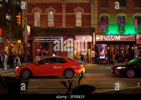 Ein Wochenendabend in der King Street im Zentrum von Toronto. Menschenmassen strömen aus Bars und Clubs, Neonlichter erleuchten das pulsierende Nachtleben der Stadt. Stockfoto