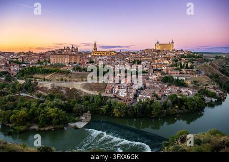 Altstadt von Toledo, Kathedrale und Alcazar über dem Fluss Tagus und einem Wehr unter einem pastellfarbenen Abendhimmel, Kastilien-La Mancha, Spanien. Stockfoto