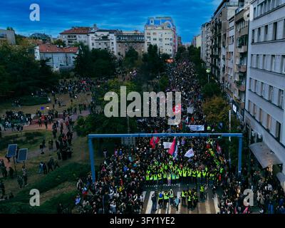 Beograd, Serbien – 22. Oktober 2026: Luftaufnahme eines massiven Protestmarsches in der Nähe des Slavija-Platzes in Belgrad, bei dem Demonstranten Fahnen tragen und Trage… Stockfoto
