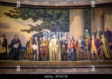 George Washington im Verfassungs-Mural im Rotunda der National Archives in Washington DC | WASHINGTON — George Washington steht im Mittelpunkt von Barry Faulkners Mural „Die Verfassung der Vereinigten Staaten“ im Rotunda der National Archives in Washington, D.C. Faulkner gruppierte die Delegierten nach den tatsächlichen Ausschüssen der Konvention, und die Inschrift, die entlang des Randes der Leinwand gemalt ist, nennt den Namen des Werkes. Stockfoto