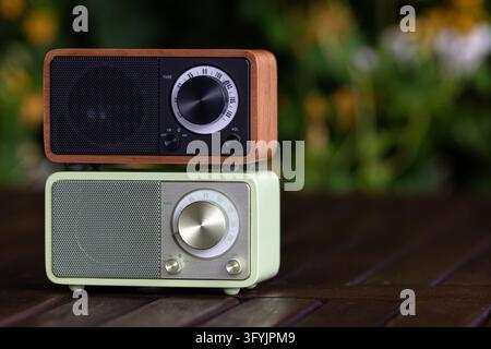 Gestapelte Vintage-Radios mit retro Tuningknöpfen, Holz- und mintgrünen Gehäusen sowie strukturierten Lautsprechergittern. Ein weicher Bokeh-Hintergrund erzeugt eine gemütliche Atmosphäre Stockfoto
