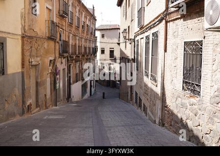 Leere schmale Straße, gepflastert mit Kopfsteinpflaster, zwischen alten Ziegel- und Steinbauten in Toledo, Spanien, die Geschichte zeigen Stockfoto