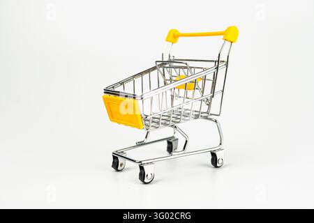 Roter, Miniatur-Einkaufswagen auf weißem Hintergrund, isoliert Online-Shopping, E-Commerce, Werbesymbol, neutrales Licht Aus Metall, vier Räder, zw Stockfoto