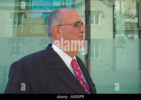 Reife Geschäftsmann im Anzug in Stadtstraße steht er neben einem modernen Glasbau Stockfoto