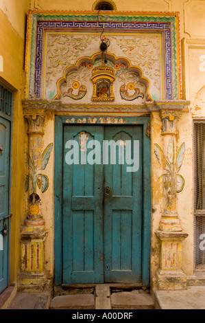 Reich bemalter Türeingang im Stadtzentrum von Varanasi Uttar Pradesh Indien. Verzierte blaue Holztür mit traditionellen indischen Schnitzereien und Wandgemälden. Stockfoto