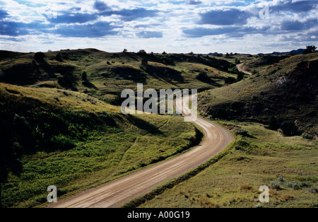 Unter endlosen Himmel bedeckt ein Land Straße Fäden durch leere Rasen Hügel von Theodore Roosevelt Nationalpark North Dakota Stockfoto