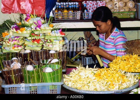 junge Mädchen Vorbereitung floral Geist Opfergaben an eine Blume Stand in Denpasar Bali Indonesien vermarkten Stockfoto