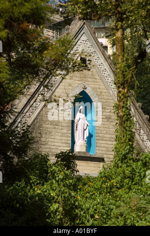 Christliche Statue der Heiligen Jungfrau in einer blauen Nische in einer anglikanischen Kirche in Darjeeling, Westbengalen, Indien. Umgeben von üppig grünem Laub. Stockfoto