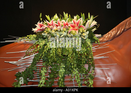 Amaryllis und Orchideen Blumenarrangement, Stillleben, geformt wie Sattel auf Tan Pferd Skulptur, schwarzer Hintergrund Stockfoto