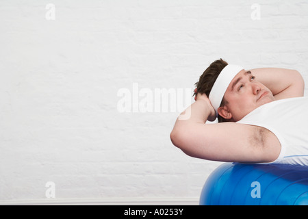 Übergewichtiger Mann Sit auf Gymnastikball Stockfoto