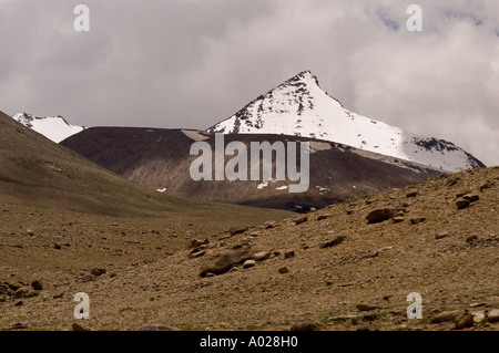 Schlechtes Wetter im Himalaya für Wanderer mit einem schneebedeckten, scharfen Berggipfel unter bewölktem Himmel in einer kargen Landschaft. Stockfoto