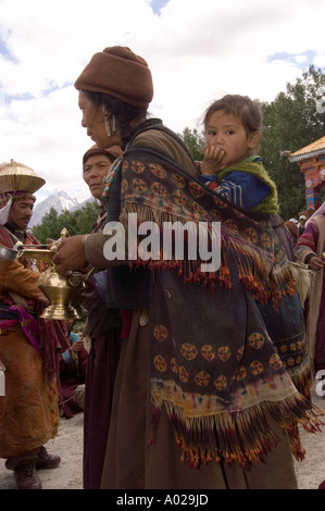 Ladakhi-Frau in traditioneller Kleidung mit einer Tochter und einem Messingtopf mit lokalem Bier bei einer Hochzeitsfeier in Zanskar, Ladakh. Stockfoto
