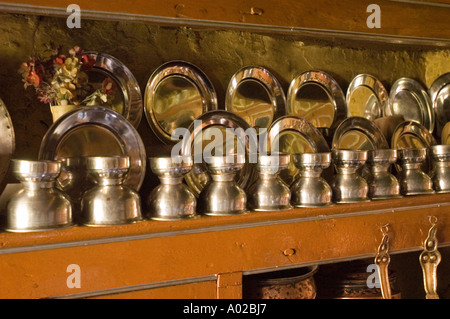 Traditionelle Messingtöpfe und -Utensilien werden auf einem Holzregal in einer traditionellen ladakhi-Küche in ladakh, Indien, ausgestellt. Stockfoto