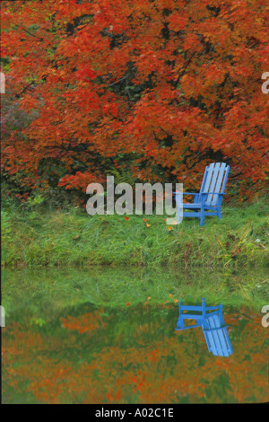 Friedliche Einsamkeit: Blau Adirondack Stuhl am Rand des ruhigen See mit Herbstlaub im Wasser spiegelt, Missouri, USA Stockfoto