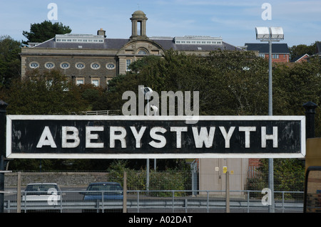 Aberystwyth Railway Station Schild mit University of Wales Kunstschule im Hintergrund, Stockfoto