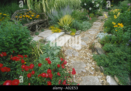 Pfad und handgemachte Willow Zweig Liebe Sitzbank in bunten Sonnengarten, akzentuiert mit Steinplatten, Midwest USA Stockfoto