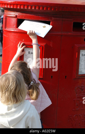 Junge Mädchen, die Entsendung in eines Briefes zu einem großen roten British Post Office box Stockfoto