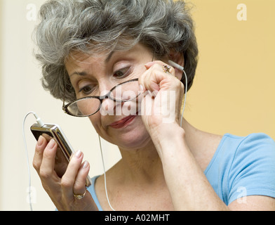 Verwirrt und frustriert Frau, die versucht, Apple Ipod MP3-Player, neue Technologie zu arbeiten Stockfoto