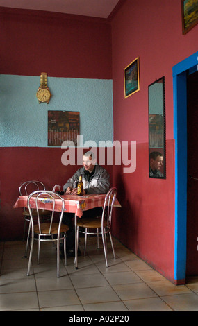 Gestrandet, Mann sitzt allein in einer Bar mit Bier Spiegel mit Mann Reflexion und Uhr montiert an der Wand Limanowa Polen Europa Stockfoto