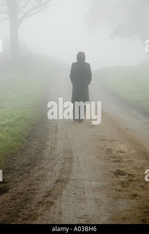 Atmosphärischen Nebel Szene einer Frau auf einer einsamen Landstraße verloren Stockfoto