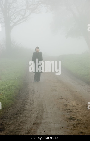 Atmosphärischen Nebel Szene einer Frau auf einer einsamen Landstraße verloren Stockfoto