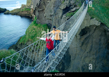 zwei jungen, die zu Fuß über Carrick ein Rede Rope Bridge an der Causeway-Küste in der Grafschaft Antrim in Nordirland Stockfoto