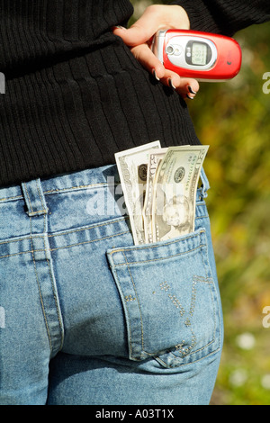 US-Dollar-Banknoten in Tasche aus einem Paar Jeans Womans Hand halten Handys Stockfoto