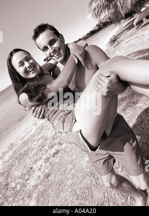 Junger Mann mit einer jungen Frau in seine Arme stehen am Strand Stockfoto