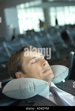 Man ruht mit Nackenkissen in Flughafen-lounge Stockfoto