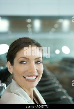 Frau in der Flughafen-Lounge, lächelnd über die Schulter Stockfoto