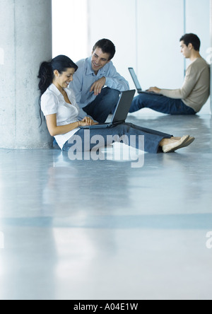 Mann und Frau Stock, mit Laptop und reden, zweiter Mann im Hintergrund Stockfoto