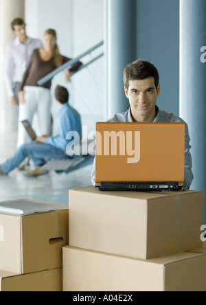 Geschäftsmann mit Laptop auf Karton Stockfoto