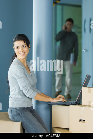 Junge Frau mit Laptop auf Karton Stockfoto